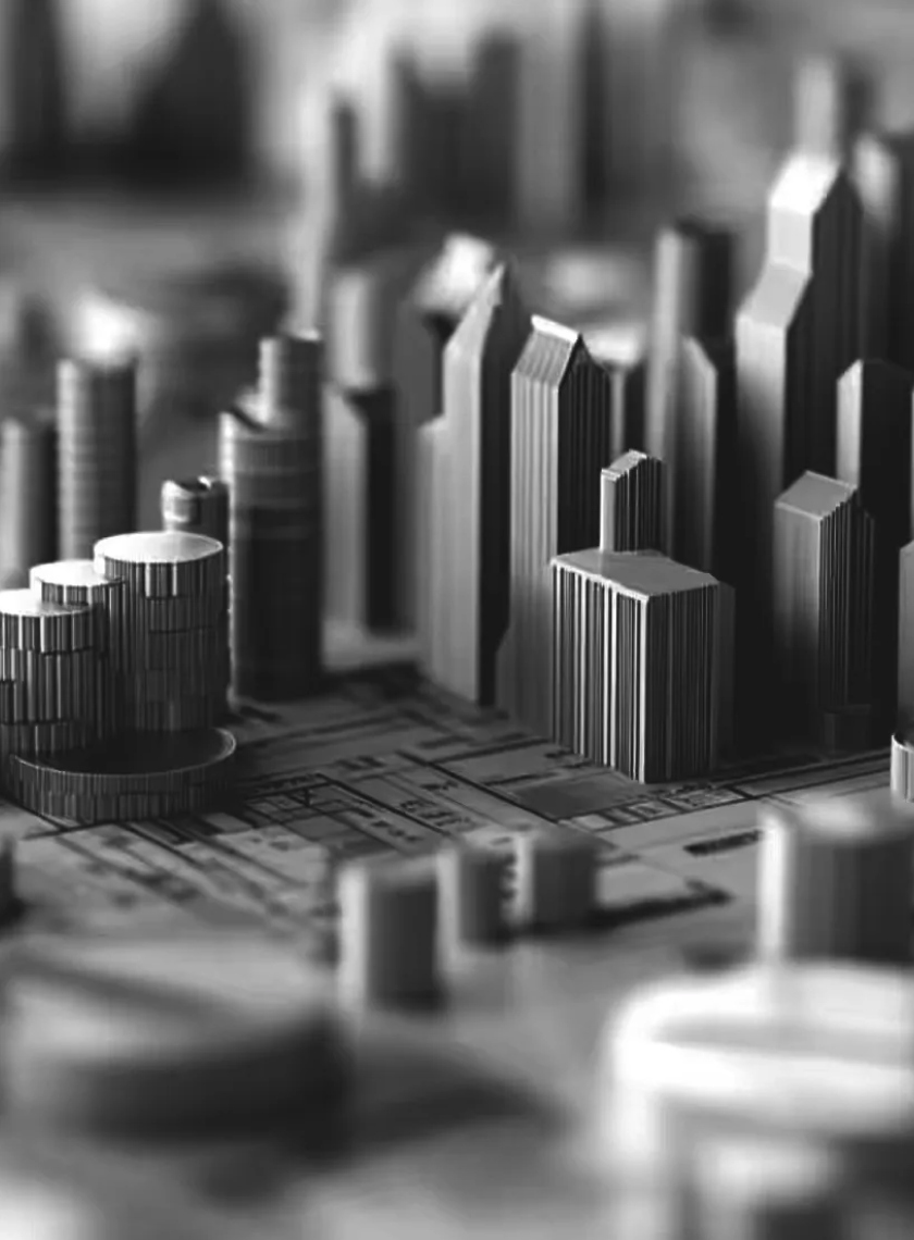 Black and white close-up of a miniature city model made from stacked paper and cardboard structures on a blueprint.